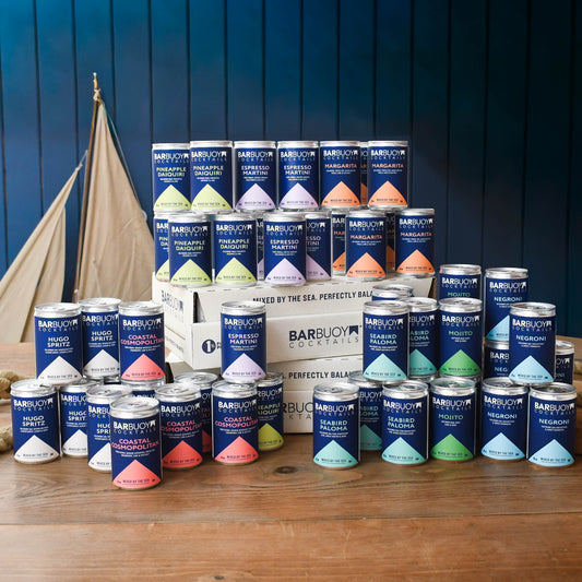 Stacks of Bar Buoy cocktail cans around a gift box
