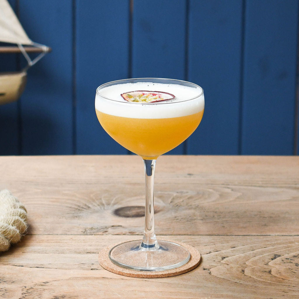 Passion Fruit Martini cocktail in a glass with a blue background