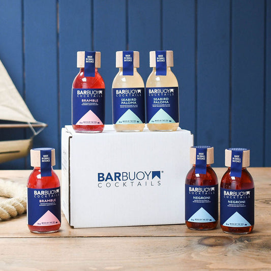 Barbuoy Cocktails bottles displayed with a white box against a blue wooden background