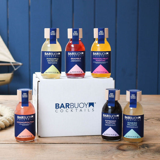 Barbuoy Cocktails bottles displayed on a wooden surface with a blue background